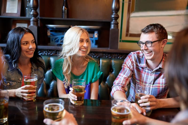 Friends laughing and talking over a beer at a pub table